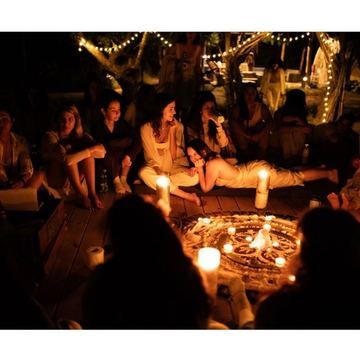 A circle of women in the evening around lit candles