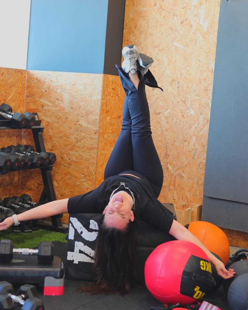 Juli lying upside down on a plyo box, legs up, laughing