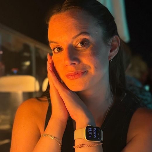 Julieta at a table in the evening, hands resting against her cheek, smiling