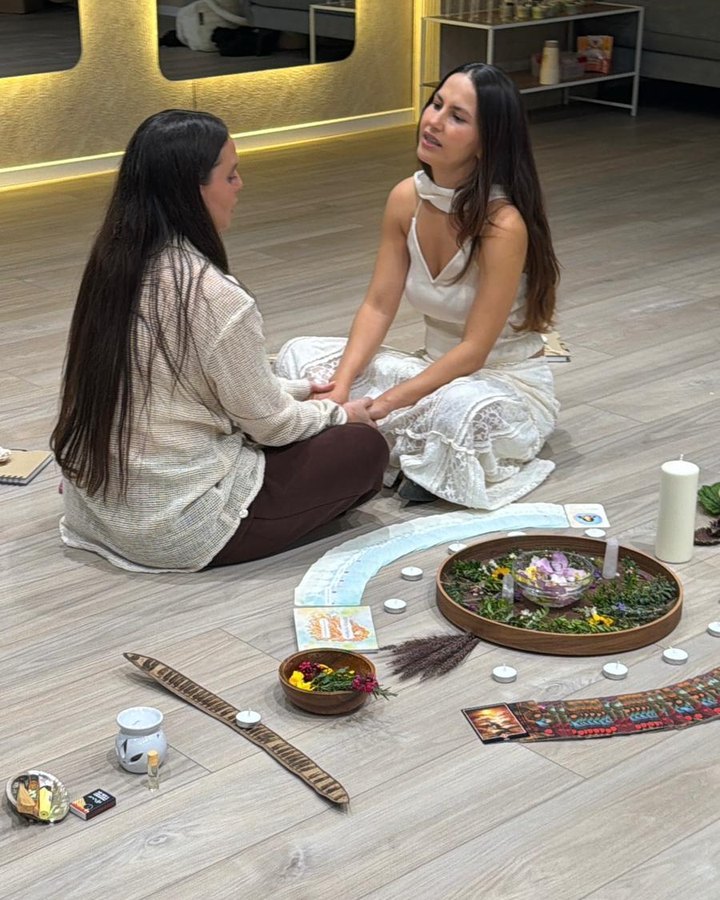 חולי יושבת מול אישה סביב מעגל של חפצי טקס